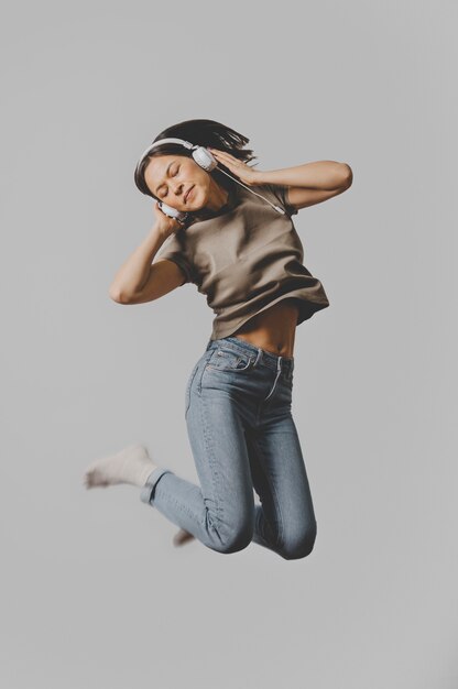 Mujer con auriculares saltando en el aire