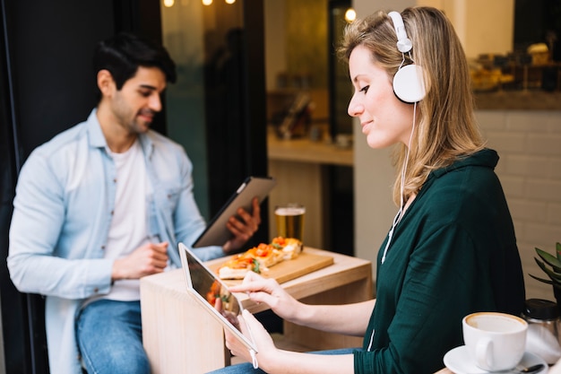 Mujer en auriculares con tableta en café