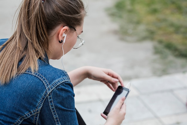 Foto gratuita mujer en auriculares con teléfono inteligente en el parque