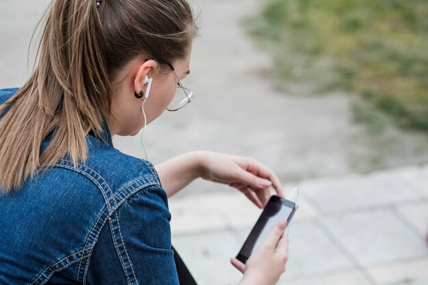 Mujer en auriculares con teléfono inteligente en el parque