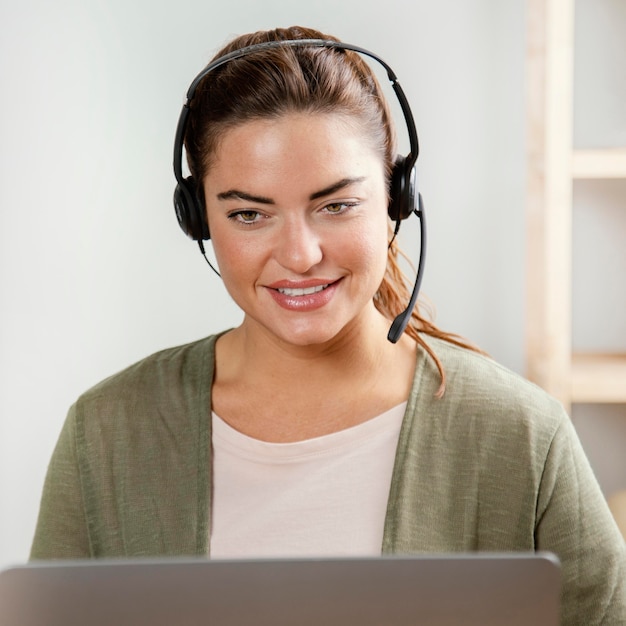 Foto gratuita mujer con auriculares usando laptop