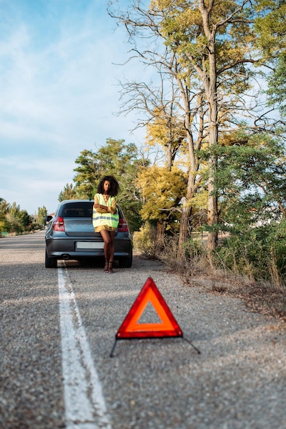 Mujer con auto roto y triángulo