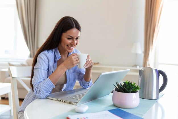 Mujer autónoma que trabaja con su computadora portátil en casa con una taza de café