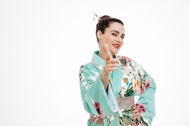 Foto gratuita mujer autosatisfecha en kimono japonés tradicional feliz apuntando con el dedo índice en blanco