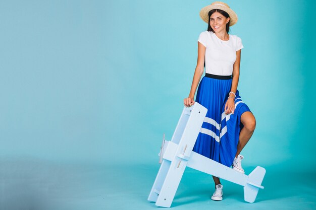 Mujer con avión de juguete sobre fondo azul