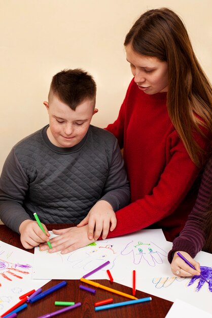 Mujer ayudando a niño con síndrome de Down dibujar