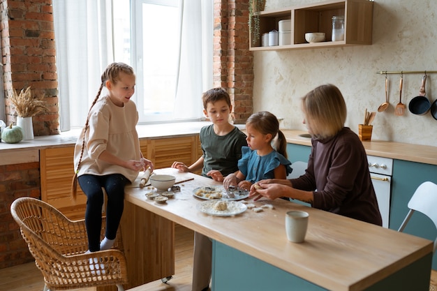 Mujer ayudando a los niños a cocinar tiro medio