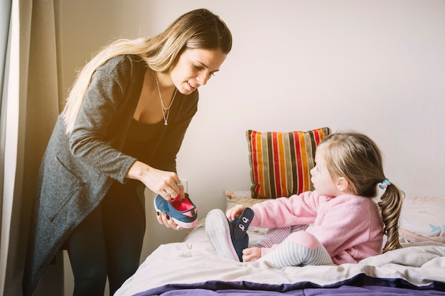 Foto gratuita mujer ayudando a su hija mientras usa zapatos