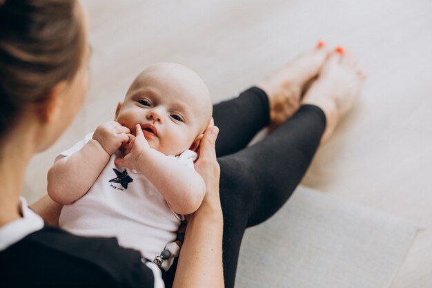 Mujer con baby boy practicar yoga