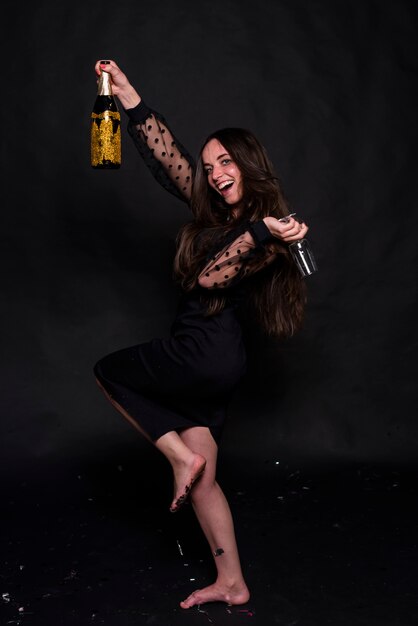 Mujer bailando con botella de champagne y copa