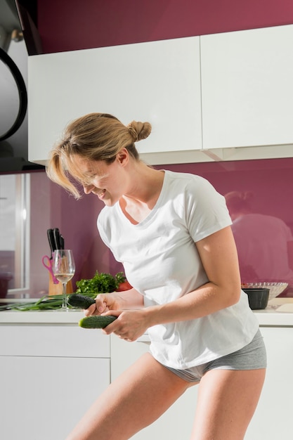 Foto gratuita mujer bailando en la cocina y sosteniendo pepinos