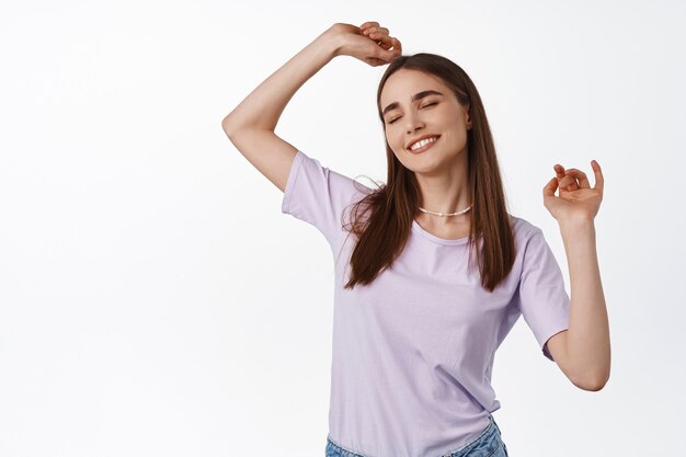 mujer bailando y sonriendo, vistiendo camiseta morada sobre blanco