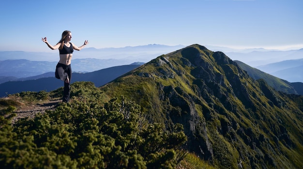 La mujer se balancea sobre una pierna en las montañas