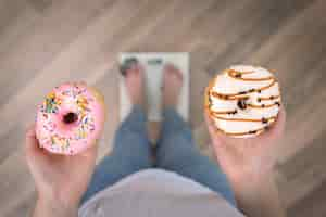 Foto gratuita una mujer se para en la balanza sostiene donas en su espacio de copia de la vista superior de las manos