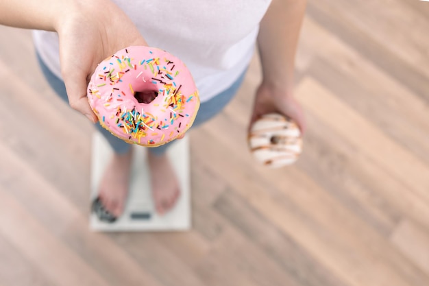 Foto gratuita una mujer se para en la balanza sostiene donas en su espacio de copia de la vista superior de las manos