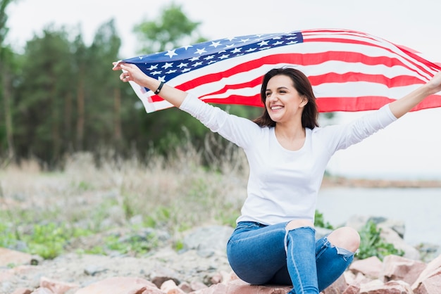 Mujer con bandera americana al lado del mar