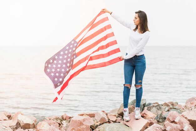 Mujer con bandera americana por el mar