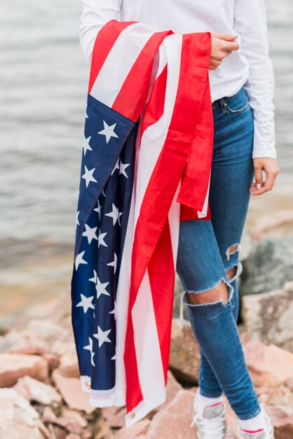 Mujer con bandera americana por el mar