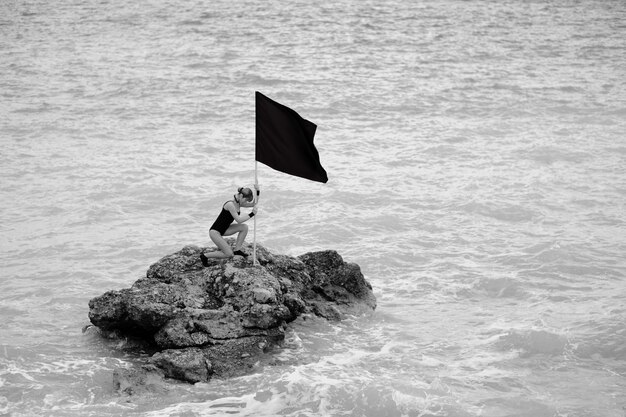 Mujer con una bandera en una roca