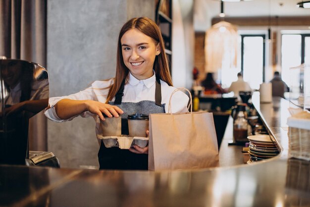 Mujer barista en la cafetería preparando café en vasos de cartón