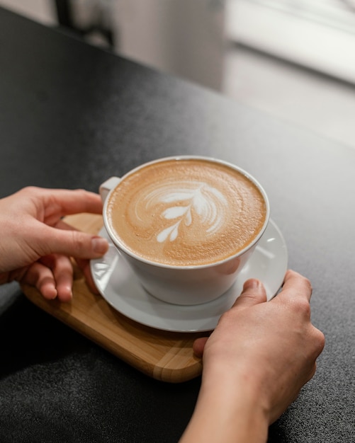 Mujer barista colocando una taza de café decorada en el mostrador