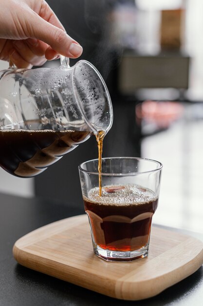 Mujer barista vertiendo café en vidrio transparente