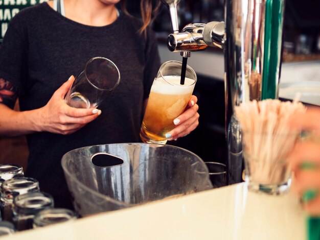 Mujer barman vertiendo cerveza