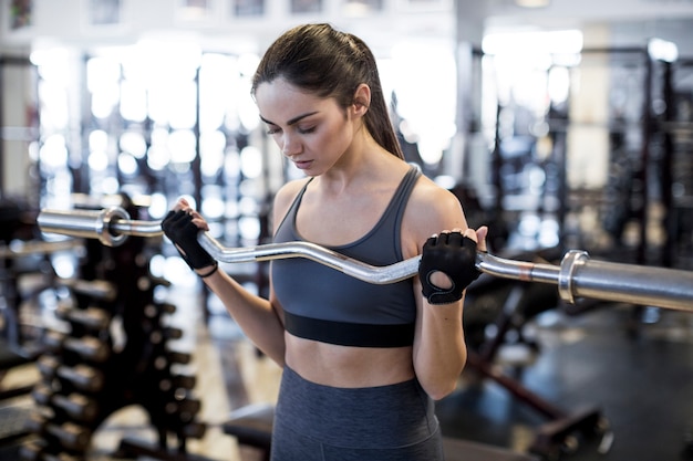 Mujer con barra en gimnasio