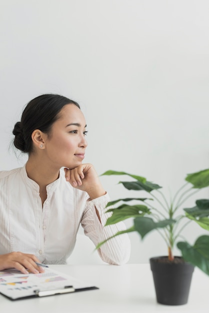 Mujer bastante asiática sentada en su lugar de trabajo