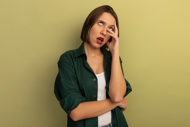 Mujer bastante caucásica molesta pone los ojos en blanco y pone las manos en la cara en verde oliva