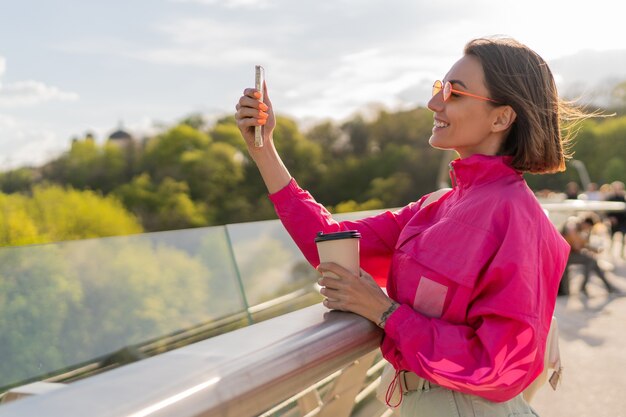 Mujer bastante deportiva en chaqueta rosa brillante caminando temprano marning al aire libre