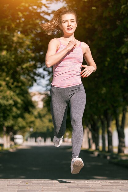 Mujer bastante deportiva trotar en el parque a la luz del amanecer