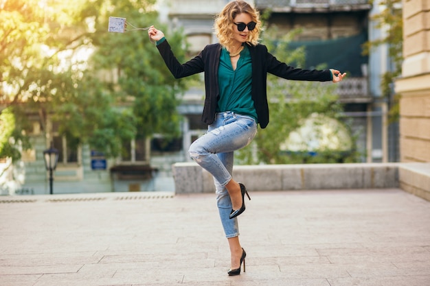 Mujer bastante elegante caminando en la calle en jeans azul con chaqueta y blusa verde, accesorios de moda, estilo elegante, tendencias de moda de primavera