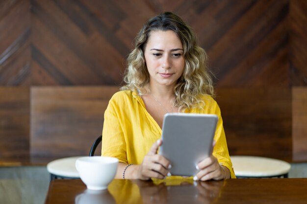 La mujer bastante joven se concentró en el libro de lectura en la tableta