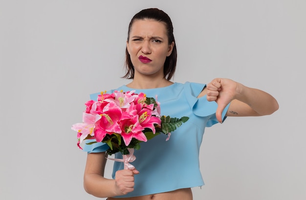 Foto gratuita mujer bastante joven descontenta con ramo de flores y pulgar hacia abajo