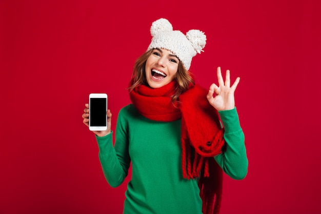 Mujer bastante joven emocionada que muestra la pantalla del teléfono