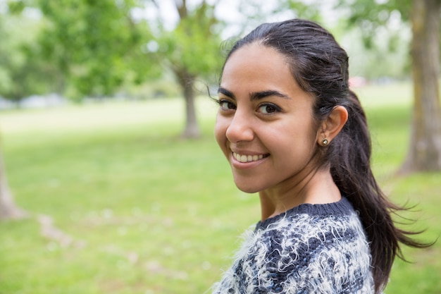 Foto gratuita mujer bastante joven feliz que presenta en la cámara en parque