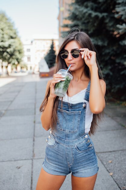 Mujer bastante joven modelo en gafas de sol y camisa en la ciudad