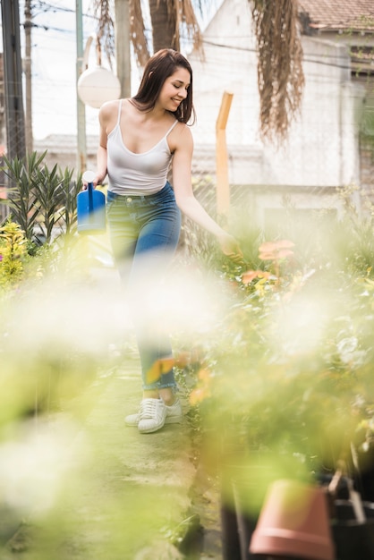 Foto gratuita mujer bastante joven que cuida de plantas en invernadero