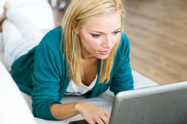 Mujer bastante joven que trabaja con la computadora portátil en el país.