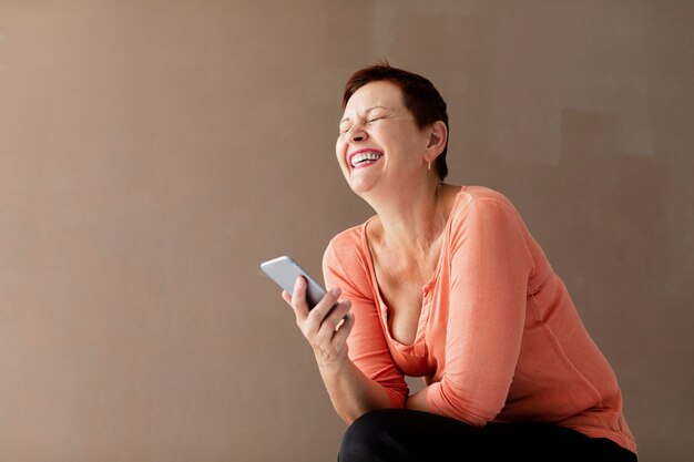 Mujer bastante madura con teléfono riendo