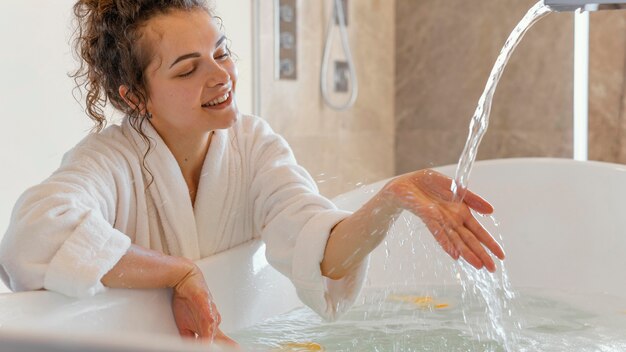 Mujer en bata de baño con la mano en el agua