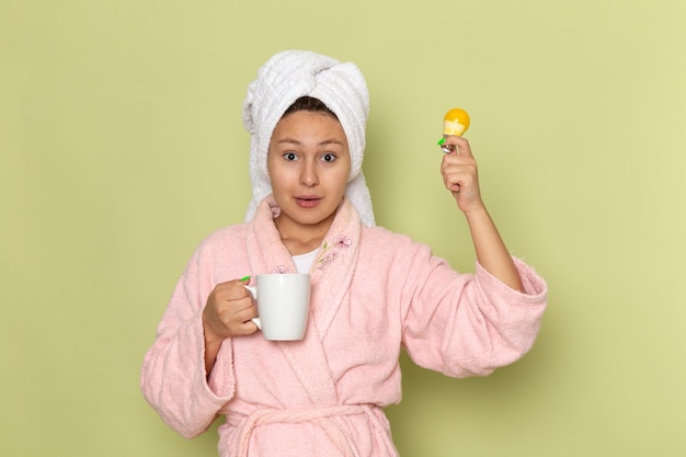 mujer en bata de baño rosa bebiendo té