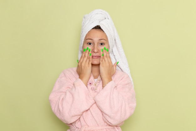 Foto gratuita mujer en bata de baño rosa frotando su cara con crema