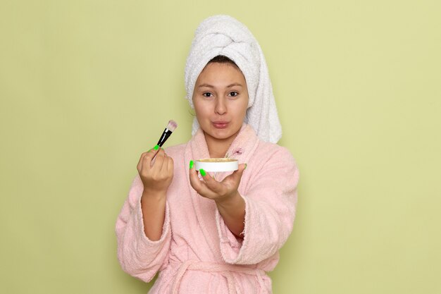 mujer en bata de baño rosa haciendo maquillaje