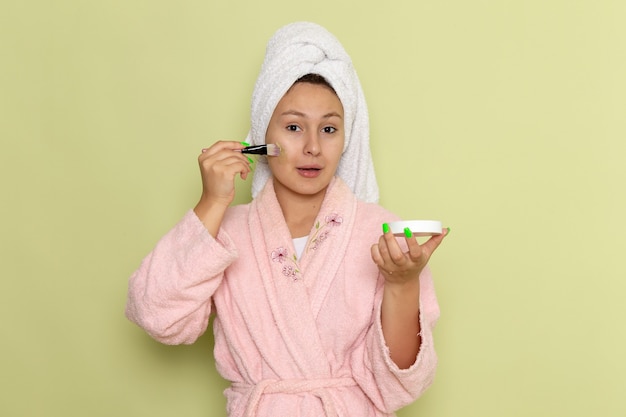 mujer en bata de baño rosa haciendo maquillaje