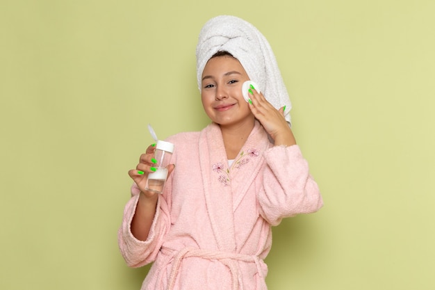 Foto gratuita mujer en bata de baño rosa limpiando todo el maquillaje de su rostro