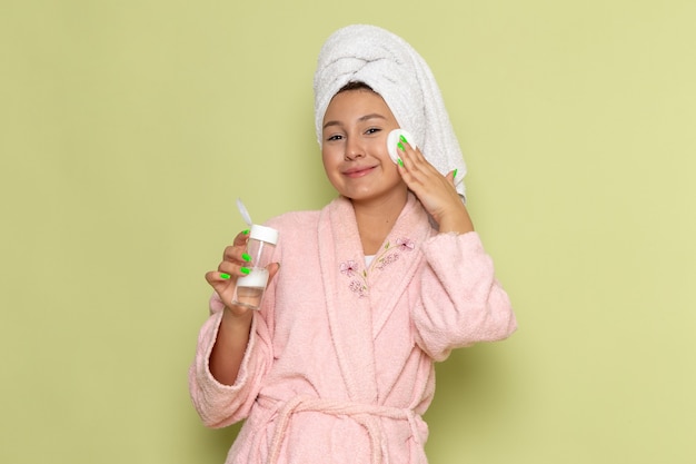 Mujer en bata de baño rosa limpiando todo el maquillaje de su rostro