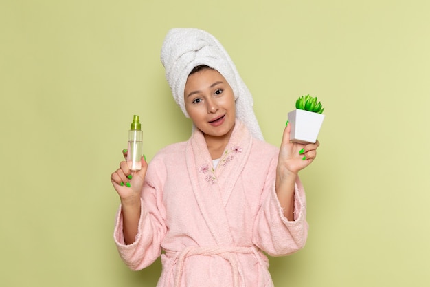 mujer en bata de baño rosa con poco spray y planta