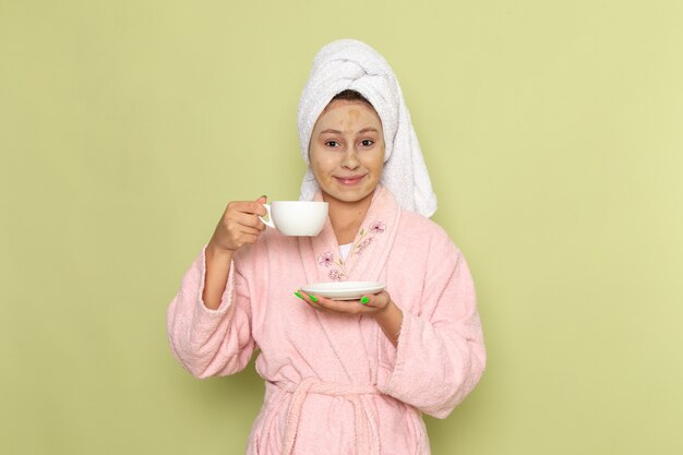 Mujer en bata de baño rosa sosteniendo una taza de café